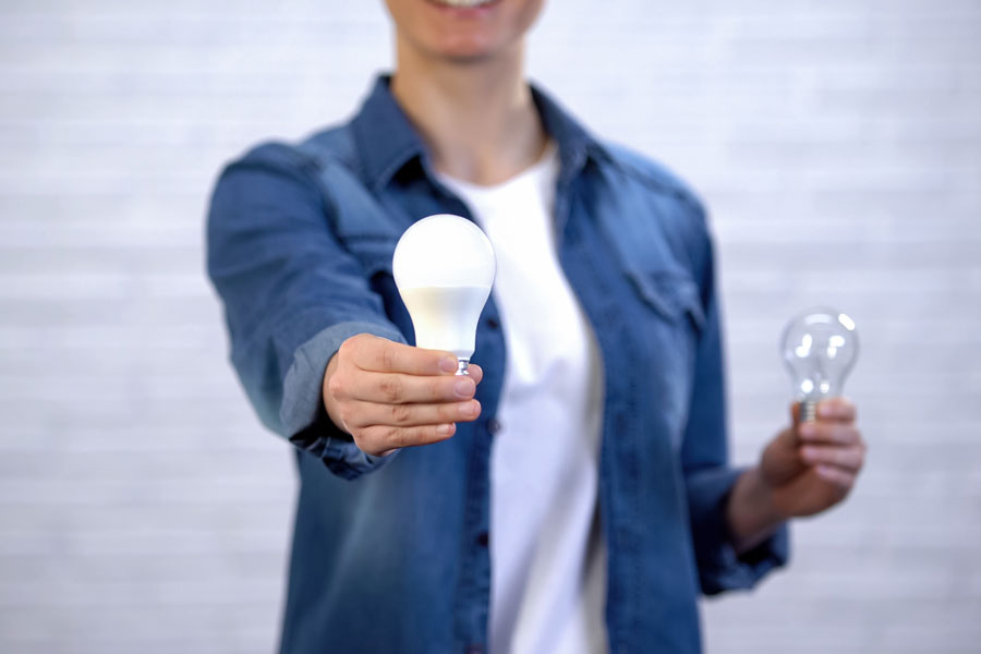 Girl chooses energy saving led bulb instead of incandescent lamp, efficiency